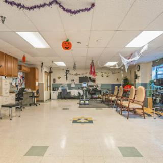 A spacious community room decorated with Halloween themed items, featuring exercise equipment and seating arrangements.