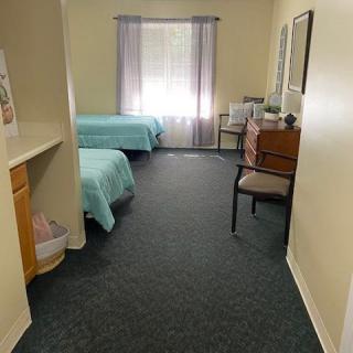 A cozy bedroom with twin beds, carpeted floor, and a window with curtains.
