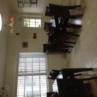 A well-lit dining room featuring a wooden dining set with chairs and large windows.