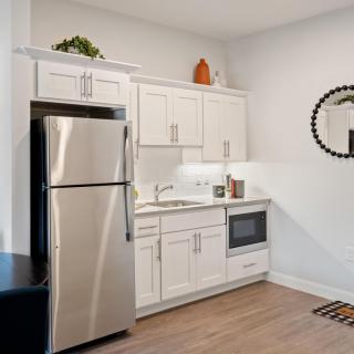 A modern kitchen with white cabinets, a stainless steel refrigerator, and a microwave.