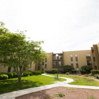 An outdoor view of an apartment building with landscaped gardens and pathways.