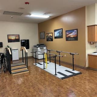 A physical therapy room equipped with exercise equipment and handrails for rehabilitation.