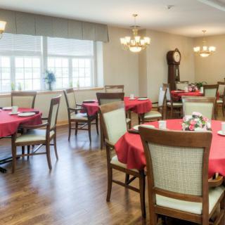 A cozy dining room with elegantly set tables covered in red tablecloths.