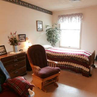 A cozy and simple bedroom featuring a bed, rocking chair, and decorative elements.