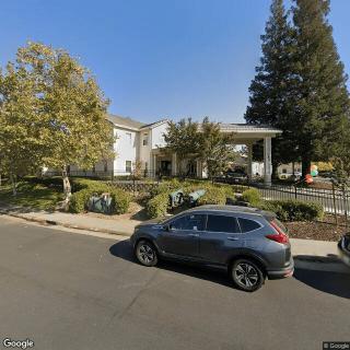 A street view of a building with trees and a parked car during the day.