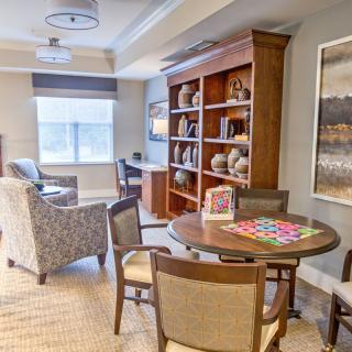 A cozy living room featuring a bookshelf, seating area, and game table.