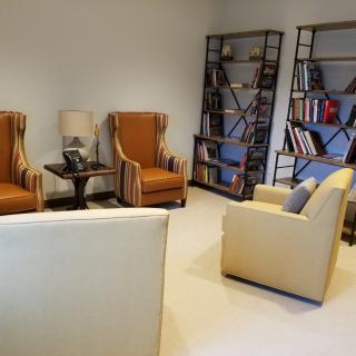 A cozy living room with armchairs, bookshelves, and a lamp.