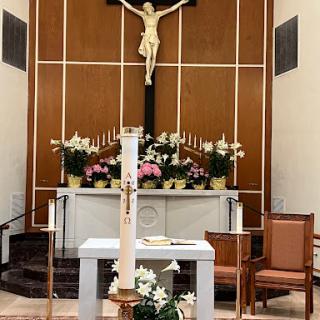 A serene view of a church altar adorned with flowers and a prominent crucifix.