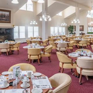 A spacious dining room with neatly arranged tables and chairs, featuring bright lighting and a cozy atmosphere.