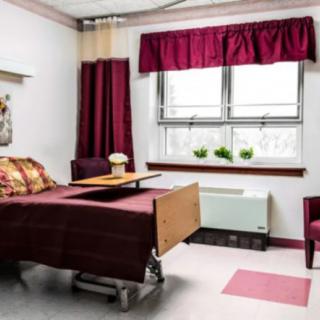 A hospital room with a bed and window covered by red curtains.