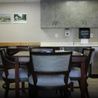 A conference room setup with a meeting table surrounded by office chairs, and cabinets in the background.