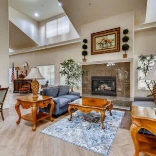 A spacious living room with modern furniture, featuring a central fireplace, a comfortable sofa set, and decorative elements.