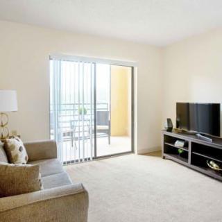 A bright living room with a sofa, TV, and sliding door leading to a balcony.