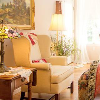 A cozy living room with traditional decor, featuring a comfortable armchair, elegant lamp, and framed painting.