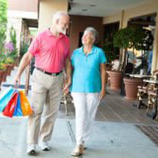 An elderly couple enjoying a day of shopping together outdoors.
