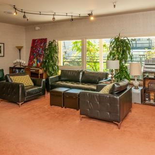 A cozy living room with leather seating, artwork, and lush plants.