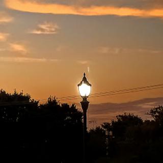 A lamp post stands illuminated against the vibrant colors of the sunset.