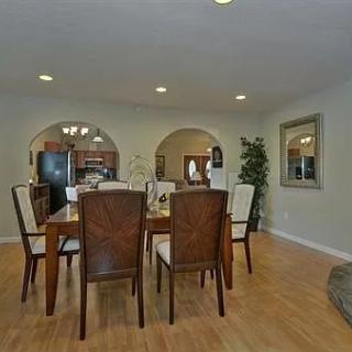 A modern dining room with a wooden table and chairs, featuring stylish decor and wood flooring.