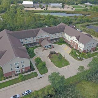 Aerial view of a large building surrounded by trees and a parking lot.