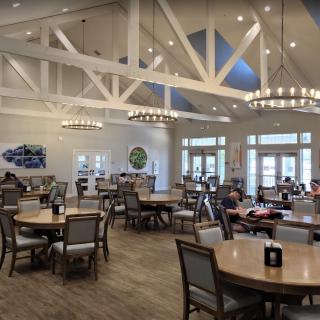 Spacious dining area with elegant lighting and neatly arranged tables and chairs.