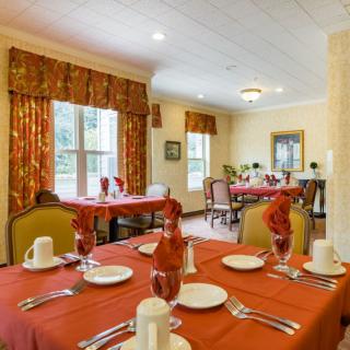 An elegantly set dining room with red tablecloths and neatly arranged tableware.