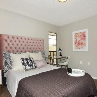 A modern bedroom with a pink tufted headboard, stylish bedding, and contemporary artwork on the wall.