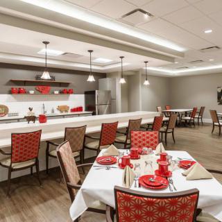 A modern dining room with red accents and neatly arranged table settings.