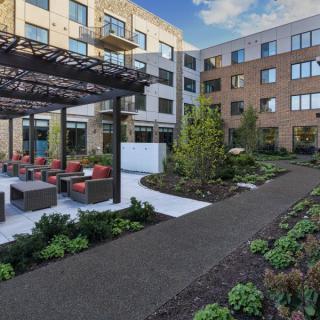 A modern apartment complex features a well-maintained outdoor seating area and landscaped gardens.