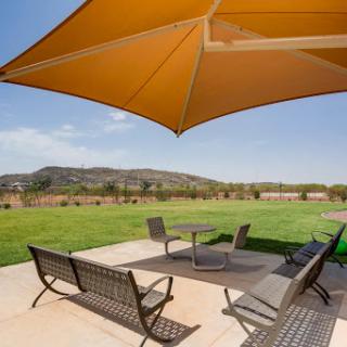 A cozy outdoor patio area featuring comfortable furniture and a large umbrella, set against a scenic backdrop of rolling hills.