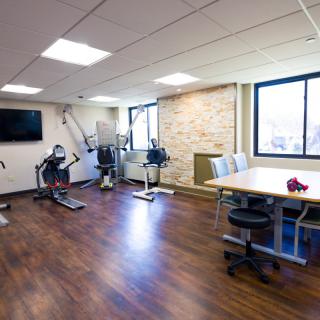 A well-lit gym room featuring exercise bikes and a workout area.