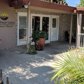A welcoming entrance to a building featuring plants and outdoor seating.