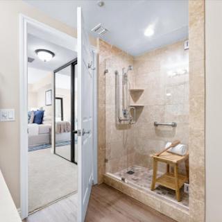 A modern bathroom featuring a stylish shower with elegant tiles and a wooden stool.