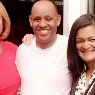 Three people smiling together outdoors.