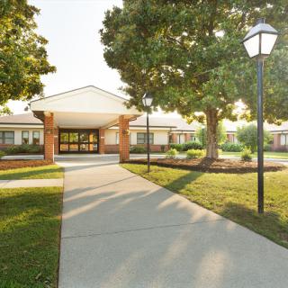 A well-maintained building with a welcoming entrance surrounded by lush greenery and lighted pathways.