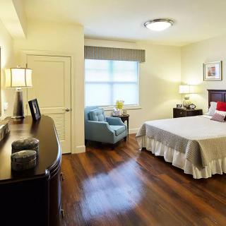 A cozy bedroom featuring a comfortable bed, wooden flooring, and soft lighting.