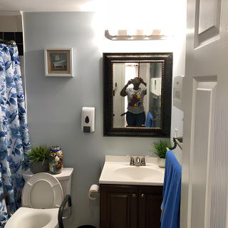 A clean and organized bathroom with a blue shower curtain, mirror, and modern fixtures.