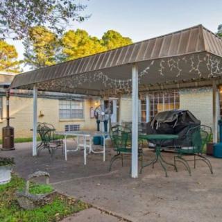 A backyard patio area with an awning, featuring outdoor furniture including chairs and a table.