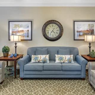A cozy living room featuring a blue sofa, decorative pillows, and matching side tables with lamps.