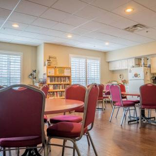 A community room with tables, chairs, and a kitchen area.