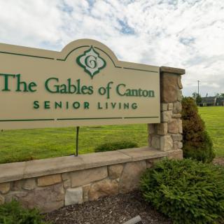 The entrance sign for The Gables of Canton Senior Living, surrounded by greenery.