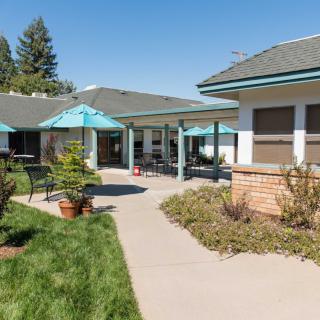 A sunny outdoor area with patios, umbrellas, and pathways between buildings.