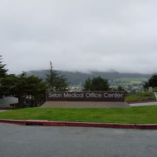 A view of the Sign Medical Office Center against a backdrop of cloudy hills.