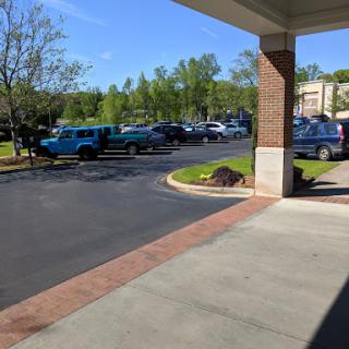A view of a parking lot with various vehicles under a clear blue sky.