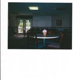 A dimly lit restaurant with a round table and a flower vase under subdued lighting.