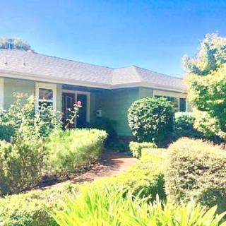 A charming house surrounded by lush greenery and a clear blue sky.