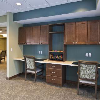 A modern office workspace with built-in desks, cabinets, and chairs.