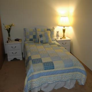 A cozy bedroom with a quilted bedspread and a warmly lit lamp on the nightstand.