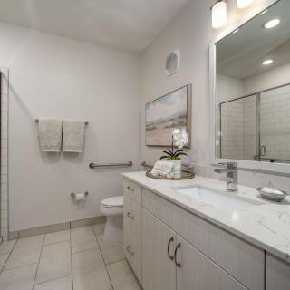 A modern bathroom with a large mirror, white cabinetry, and neatly arranged towels.