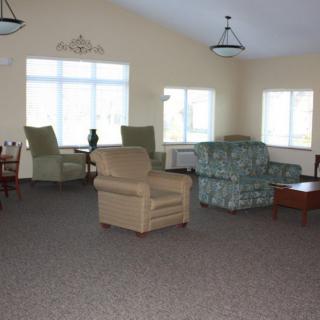 A cozy living room with a variety of seating options including armchairs and a sofa, well-lit by large windows.
