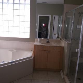 A modern bathroom featuring a bathtub, shower, and sink with a mirror.